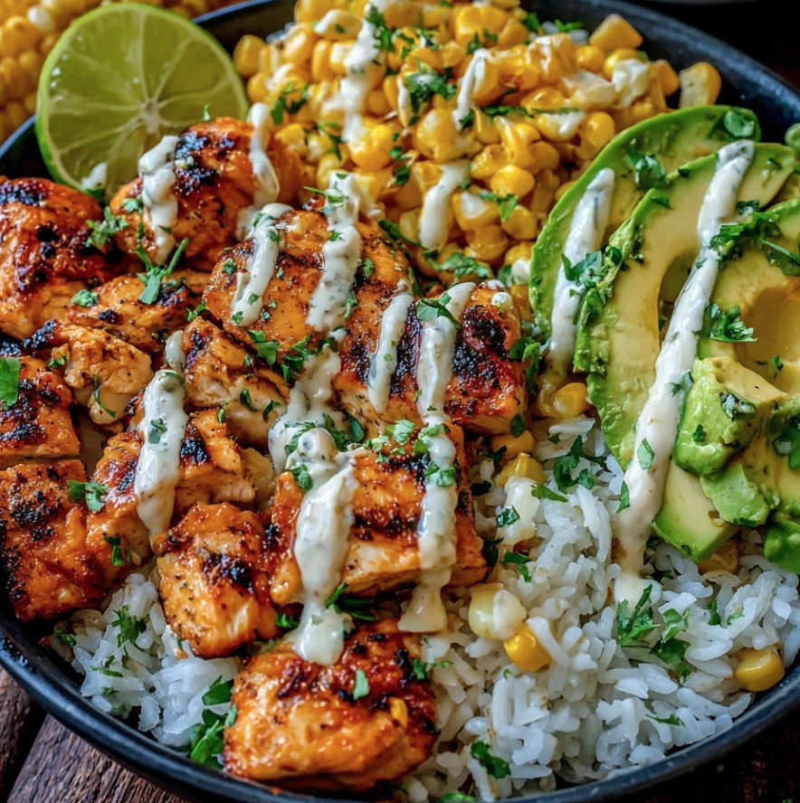 Ein Street Corn Chicken Rice Bowl mit verschiedenen Zutaten wie Avocado, Lime, Koriander, Rice, Chicken und Kartoffeln.