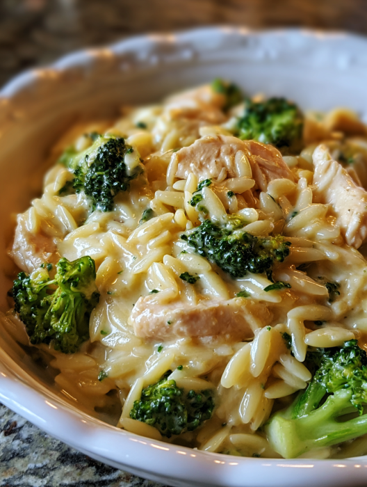 A bowl of pasta with broccoli and chicken.