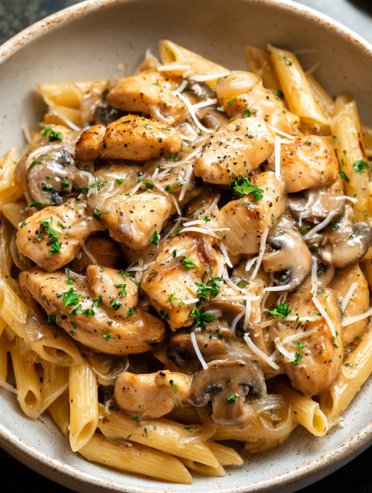 A plate of pasta with chicken and mushrooms.