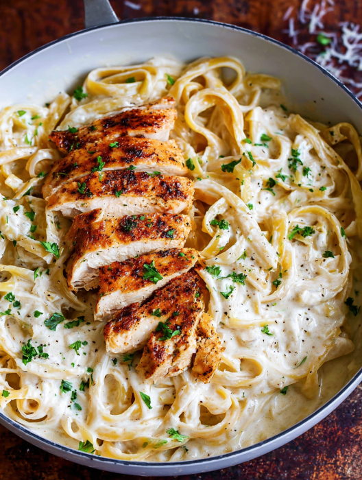 A bowl of pasta with chicken and herbs.