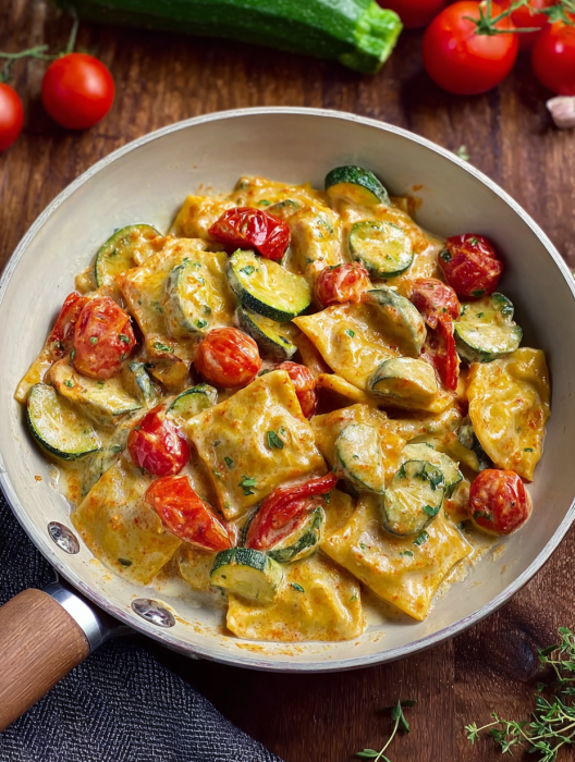A pan of food with tomatoes and zucchini.