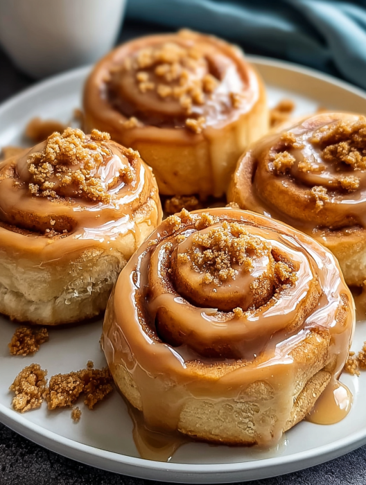 Three cinnamon rolls with icing on a plate.