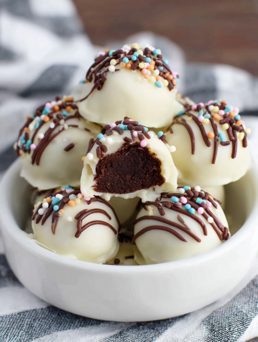 A bowl of chocolate and white frosted cake balls.