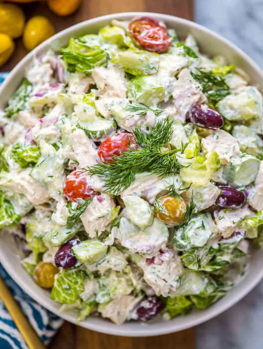 A bowl of salad with lettuce, tomatoes, and olives.