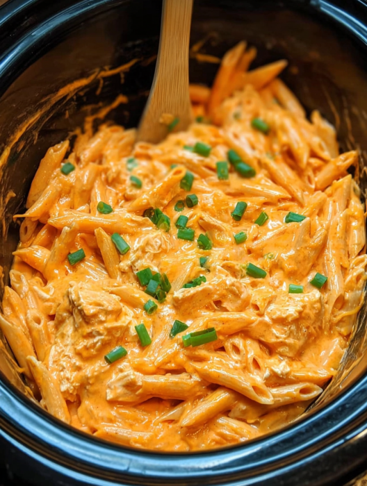 A bowl of pasta with a wooden spoon in it.