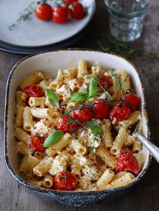 A bowl of pasta with tomatoes and cheese.
