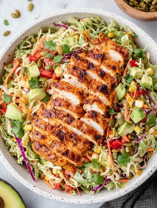 A bowl of salad with chicken and vegetables.