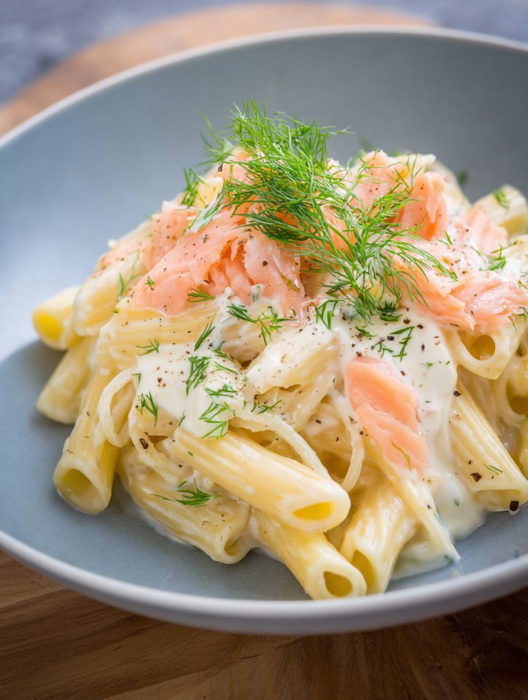 A plate of pasta with a sprig of parsley on top.