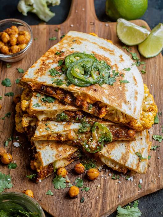 A stack of burritos with green peppers and onions.