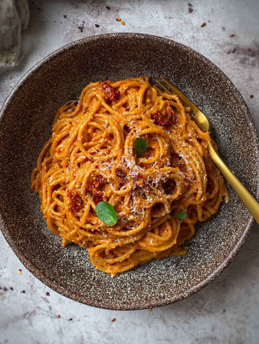 A plate of spaghetti with tomato sauce and cheese.