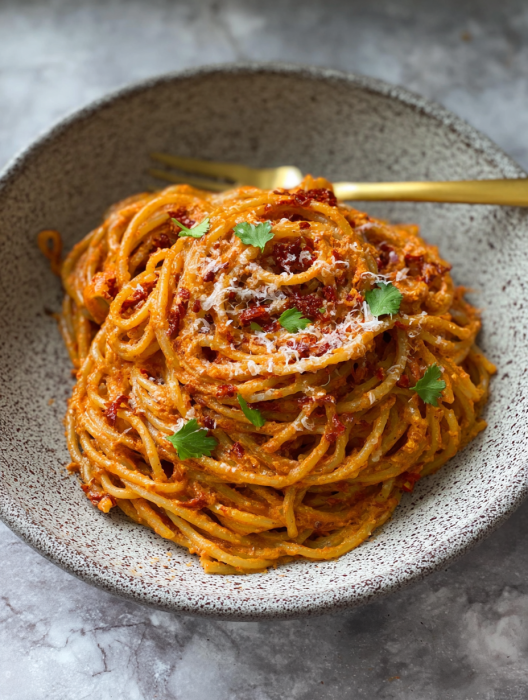 A bowl of spaghetti with tomato sauce and cheese.