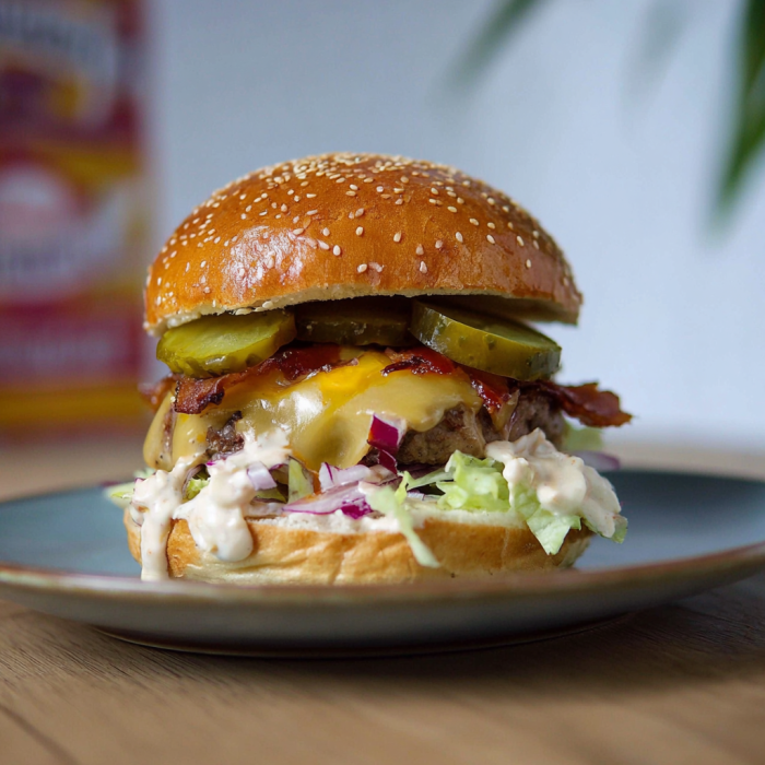 A burger with lettuce, tomato, pickles, and bacon.