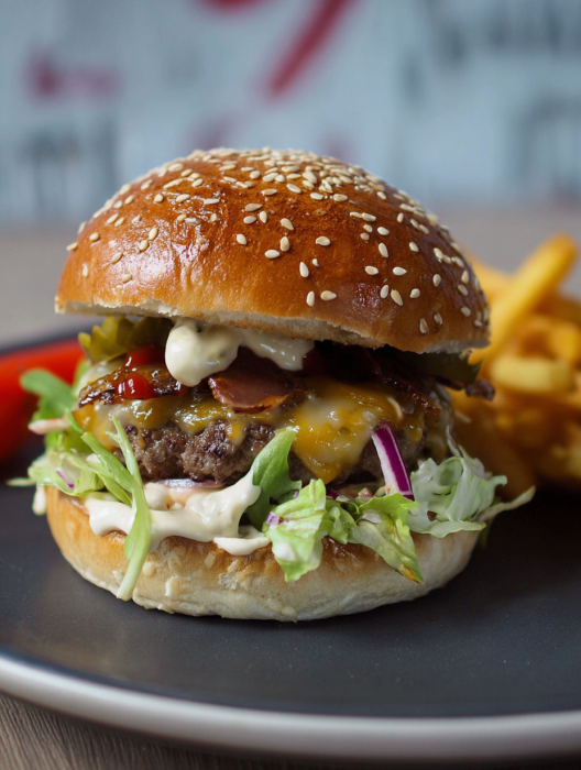 A burger with lettuce, tomato, and bacon.