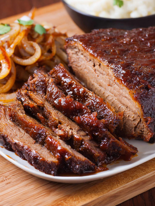 A plate of beef brisket with onions and barbecue sauce.