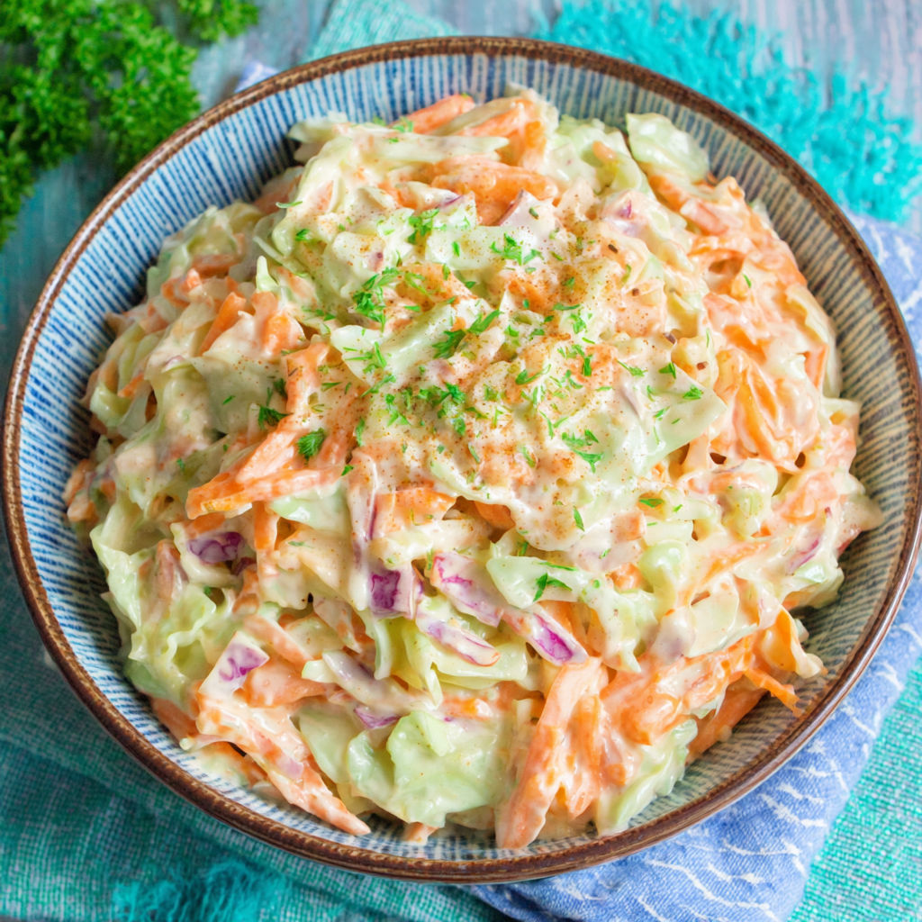 A bowl of coleslaw with a green garnish.