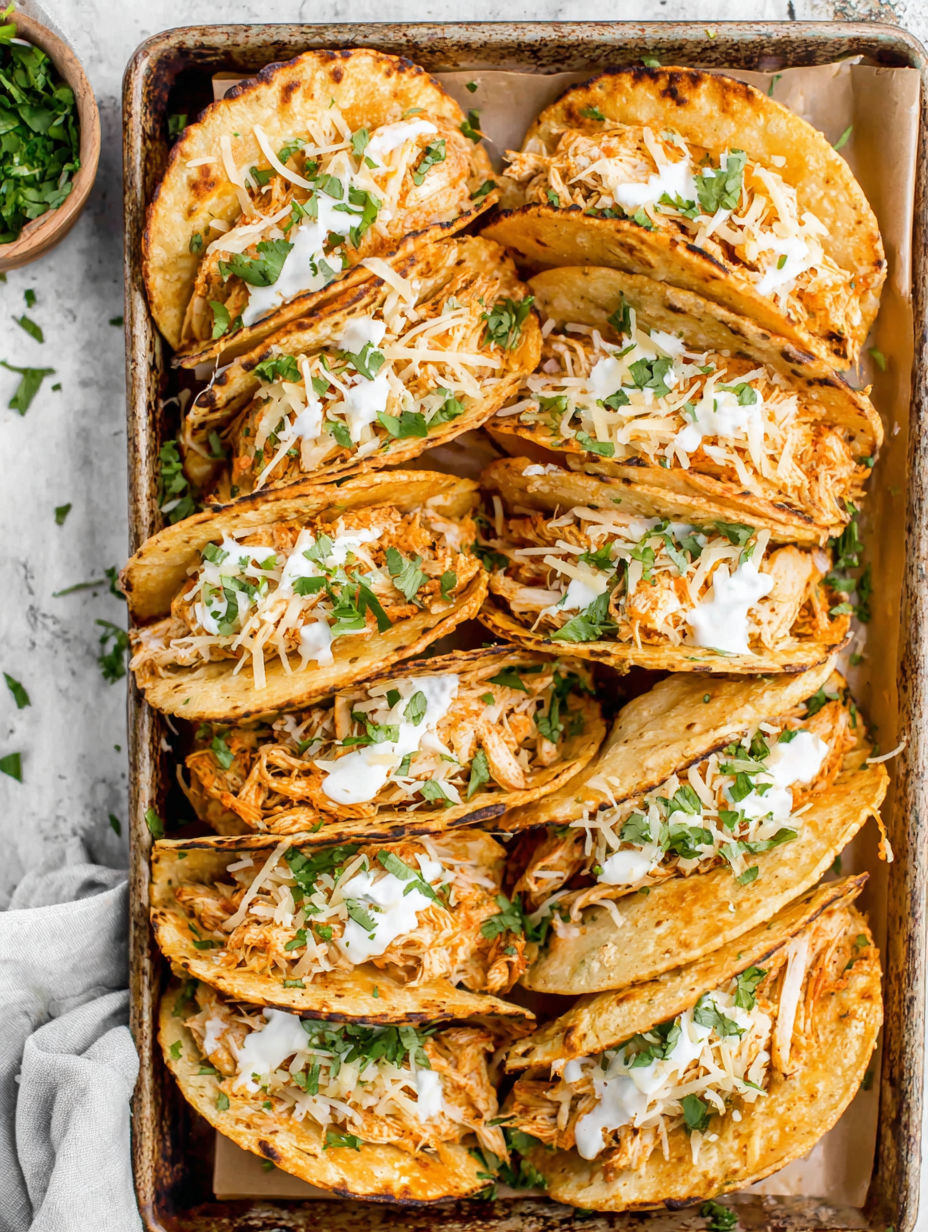 A pan of chicken tacos with white cheese and green onions.