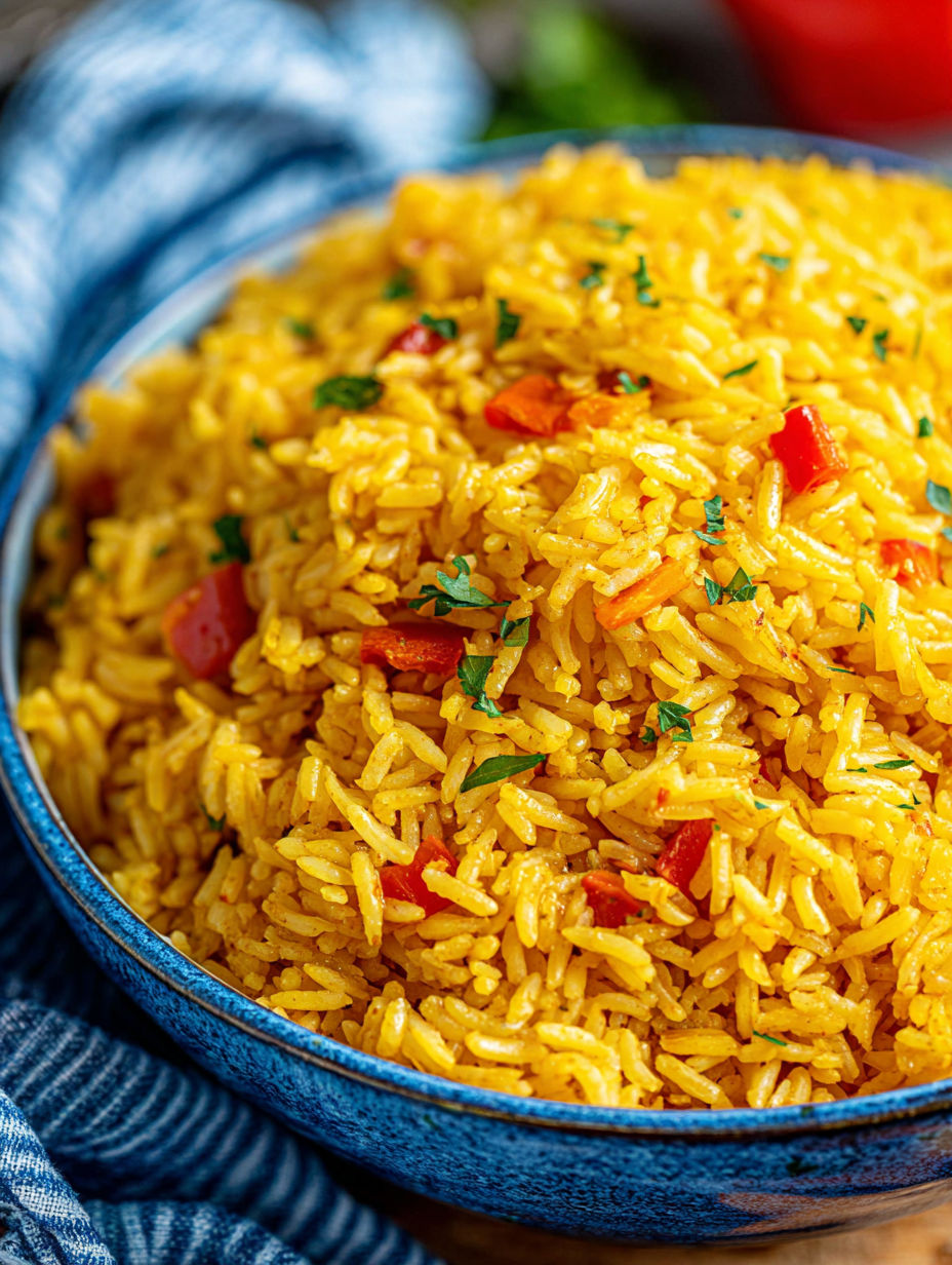 A bowl of yellow rice with green herbs on top.