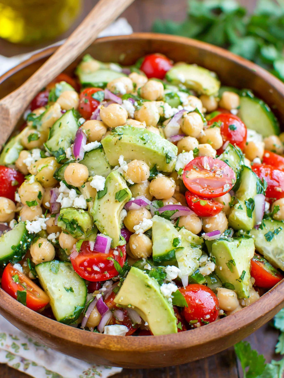 A bowl of chickpea salad with tomatoes, onions, and avocado.