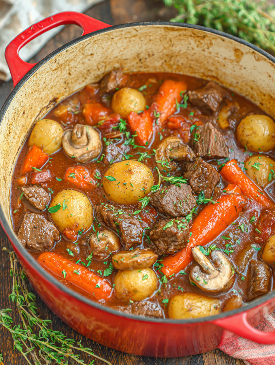 A pot of beef stew with carrots and mushrooms.