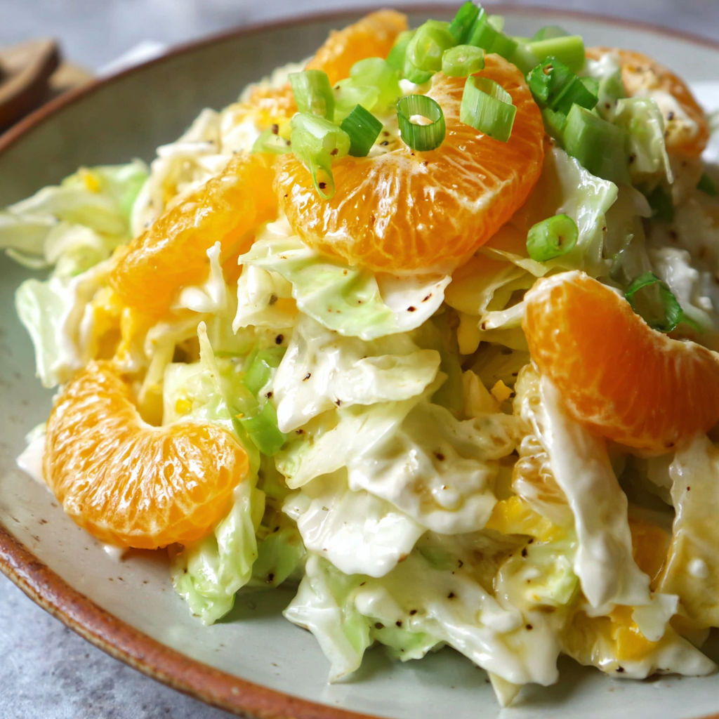 A bowl of salad with oranges and lettuce.