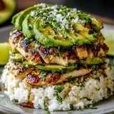 Ein Stapel aus Hühnchen, Avocado, Reis und Limetten.