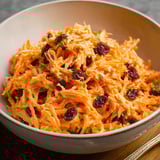 A bowl of carrot raisin salad.