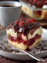 A slice of cake with chocolate and raspberry toppings.