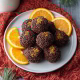 A plate of chocolate truffles with orange slices.