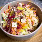 A bowl of vegetables with a white substance on top.