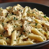 A bowl of pasta with chicken and herbs.
