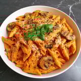 A bowl of creamy penne rosa with mushrooms and basil.