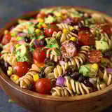 A bowl of pasta salad with tomatoes, corn, and black beans.