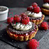 A close up of a black sesame and raspberry tart.