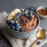 A bowl of chocolate protein fluff with bananas and blueberries.