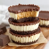 Three mini peanut butter cup cheesecakes stacked on a wooden table.
