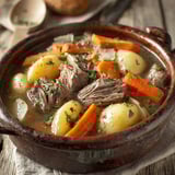 A pot of beef stew with carrots and potatoes.
