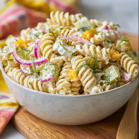 A bowl of pasta salad with dill pickles.