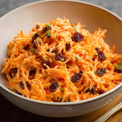 A bowl of carrot raisin salad.