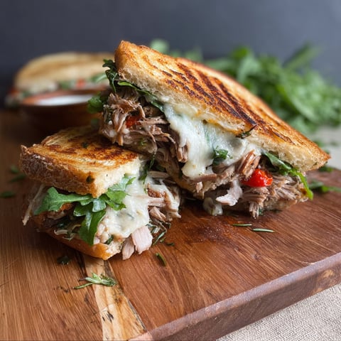 A sandwich with meat and cheese on a wooden board.