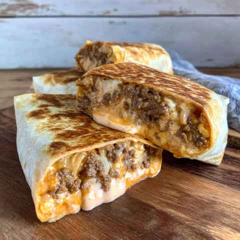 A burrito with meat and cheese on a table.