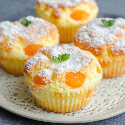 A plate of muffins with powdered sugar on top.