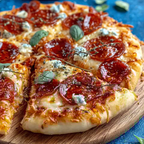 A slice of pepperoni pizza with blue cheese on a wooden cutting board.
