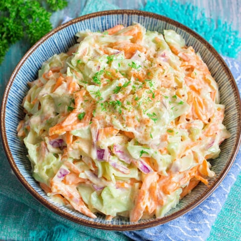 A bowl of coleslaw with a green garnish.