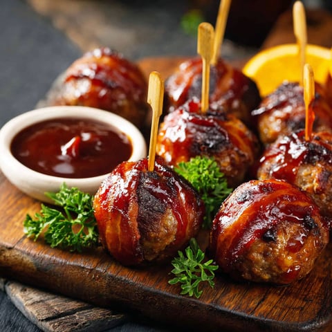 Bacon wrapped meatballs with a dipping sauce.