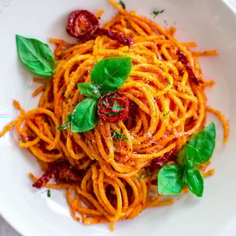 A plate of spaghetti with tomatoes and basil.