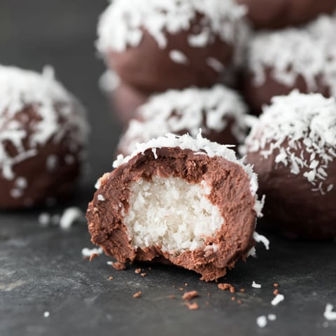 A close up of a chocolate covered ball with white cream inside.