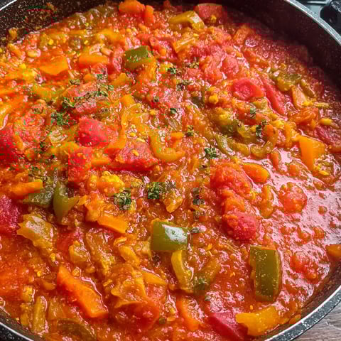 A pot of chakalaka with tomatoes, peppers, and onions.