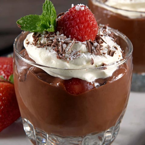 A glass of chocolate mousse with strawberries on top.