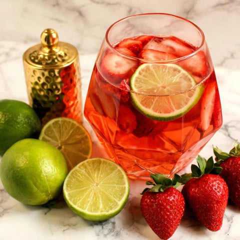 A glass of Rosé Strawberry Lime Sangria with a slice of lime in it.