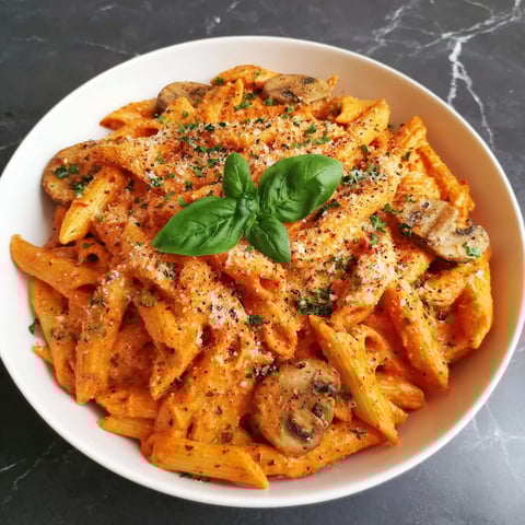 A bowl of creamy penne rosa with mushrooms and basil.
